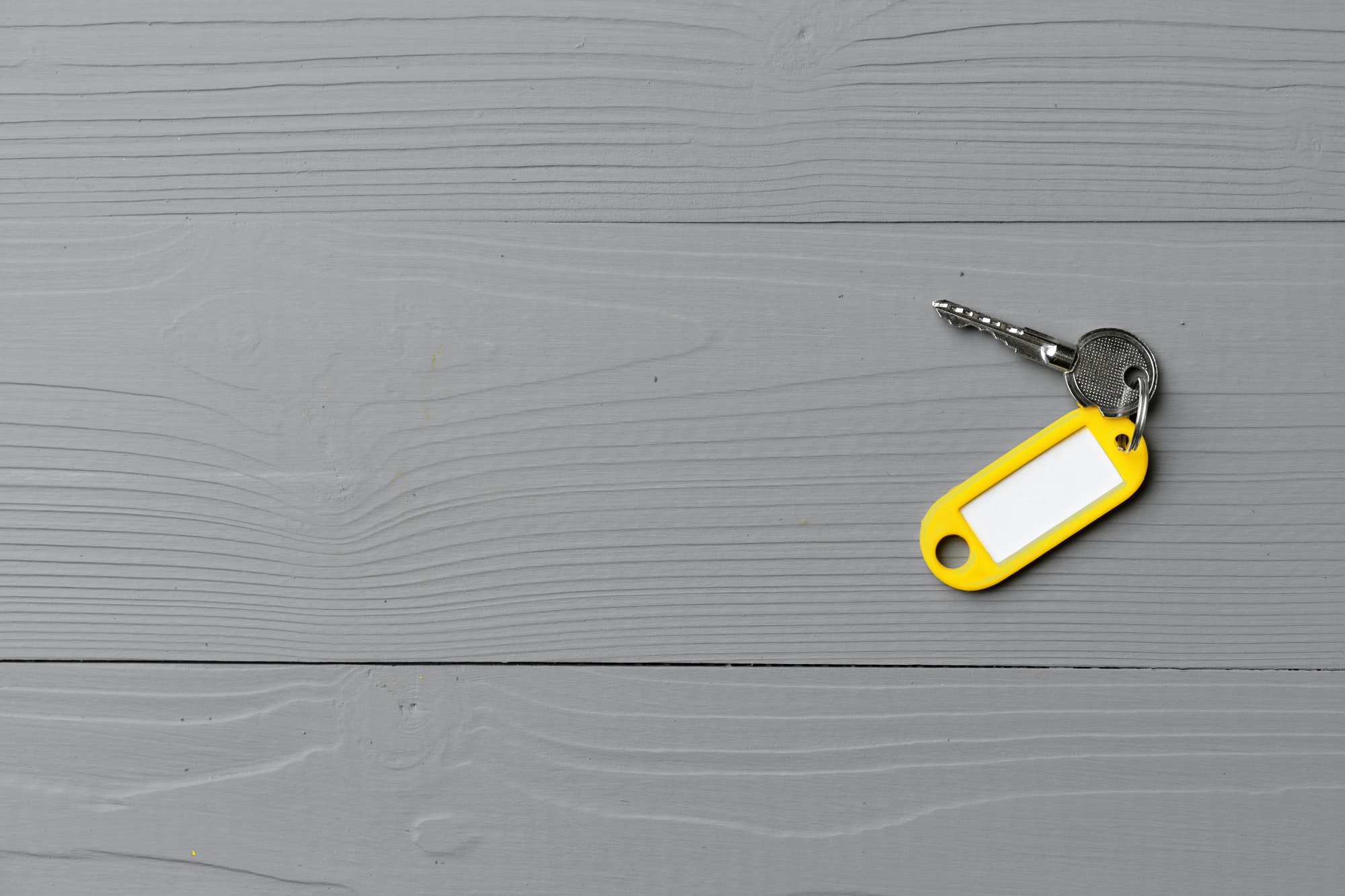 Yellow door key on gray wooden background